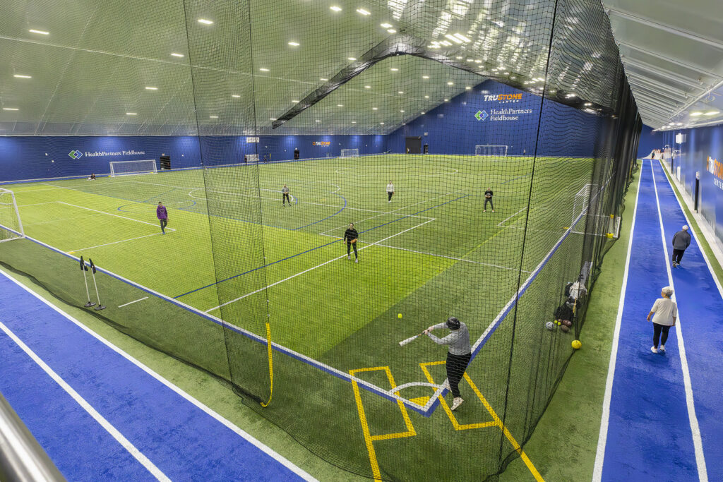 A group of people playing a baseball game at a municipal indoor fieldhouse